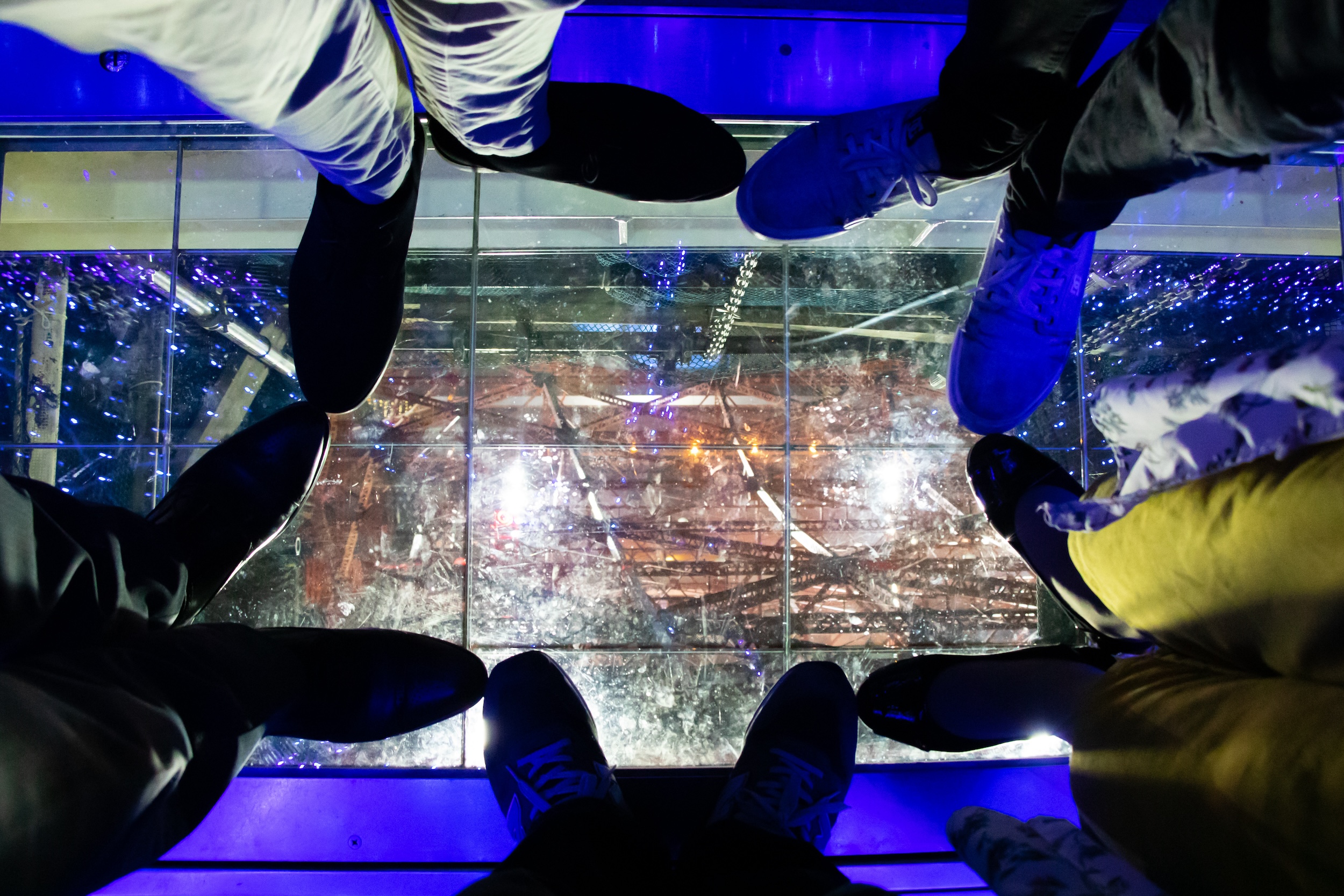 Visitors standing on the glass floor at Tokyo Tower, viewing the illuminated structure below.