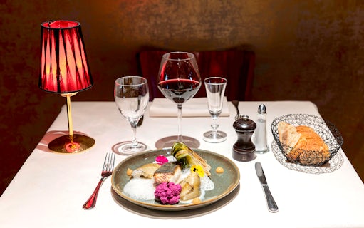 Dinner table set with gourmet dish, wine, and bread at Paris Bel Canto Opera Show.