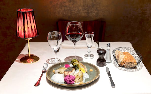 Dinner table set with gourmet dish, wine, and bread at Paris Bel Canto Opera Show.