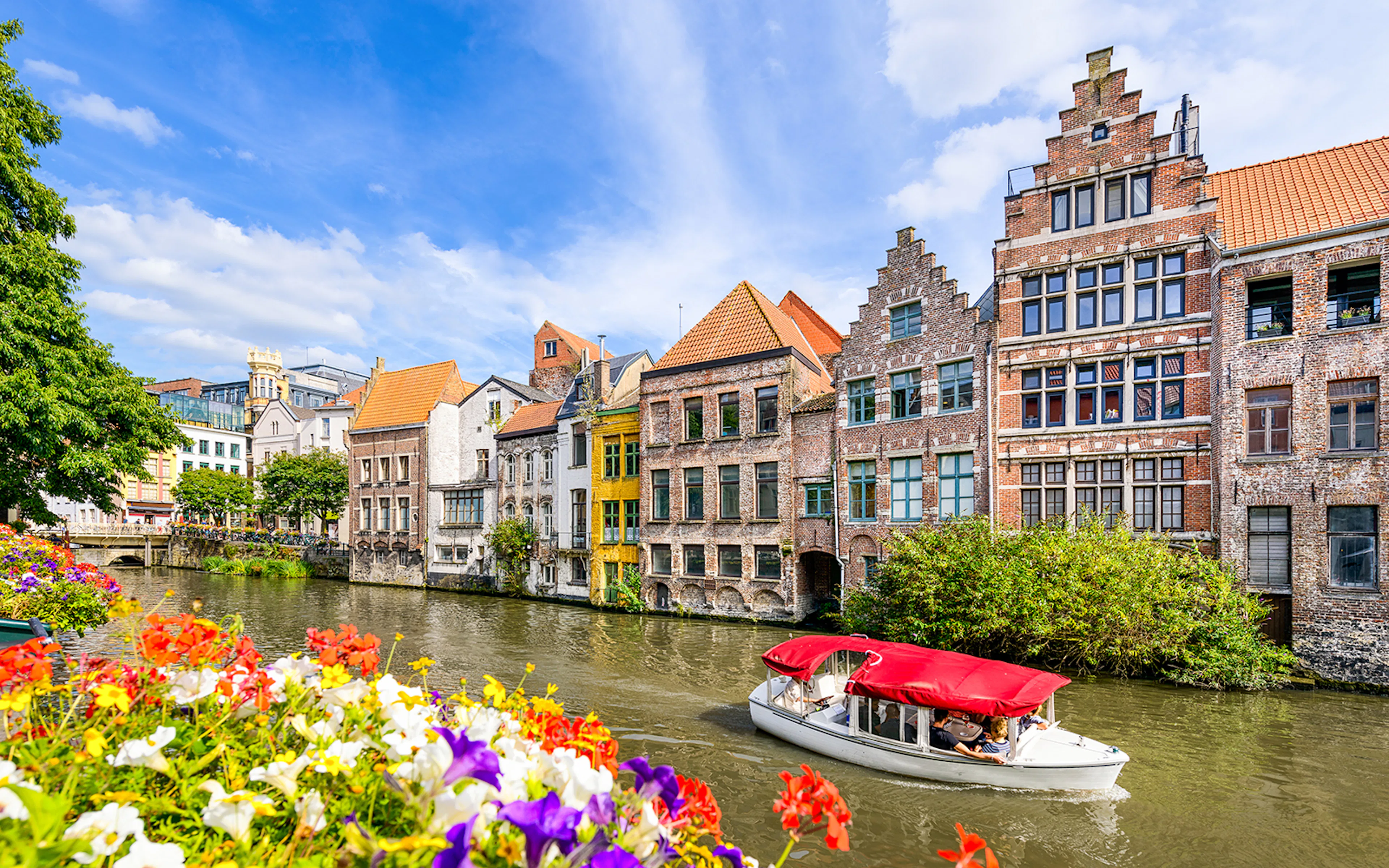 Canal boat passing historic buildings in the old town of Ghent, Belgium.