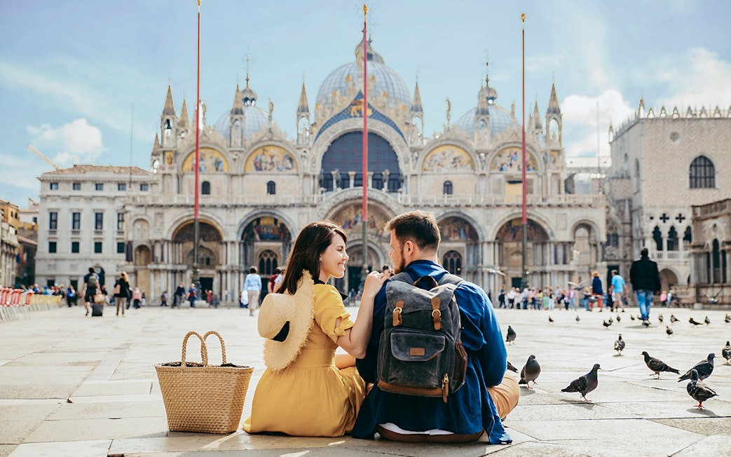Tourists sitting outside St Mark's Basilica in Venice, Italy.