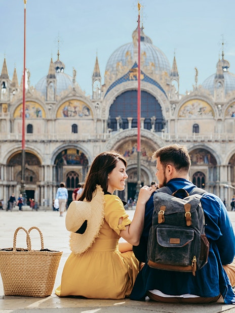 Tourists sitting outside St Mark's Basilica in Venice, Italy.