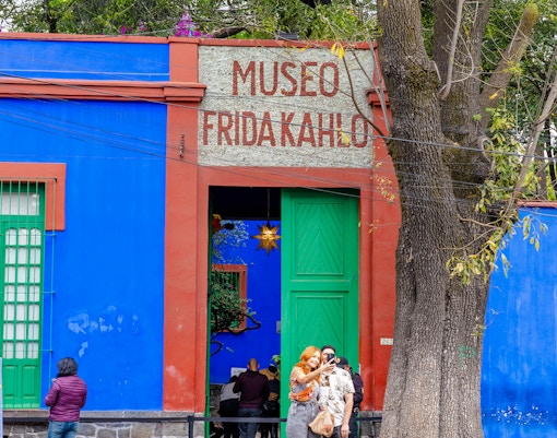 Visitors exploring the vibrant courtyard of the Frida Kahlo Museum in Mexico City.
