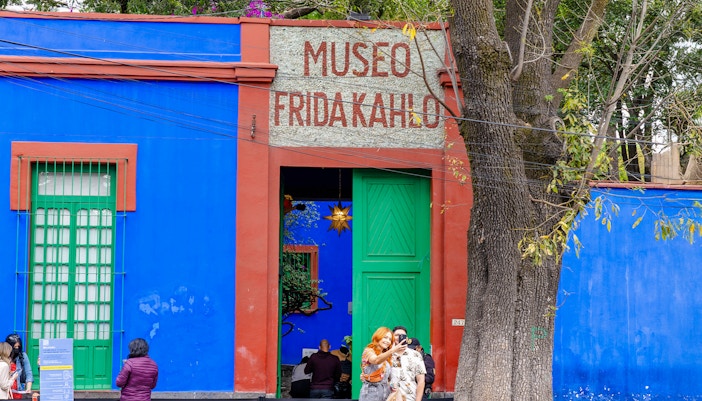 Visitors exploring the vibrant courtyard of the Frida Kahlo Museum in Mexico City.