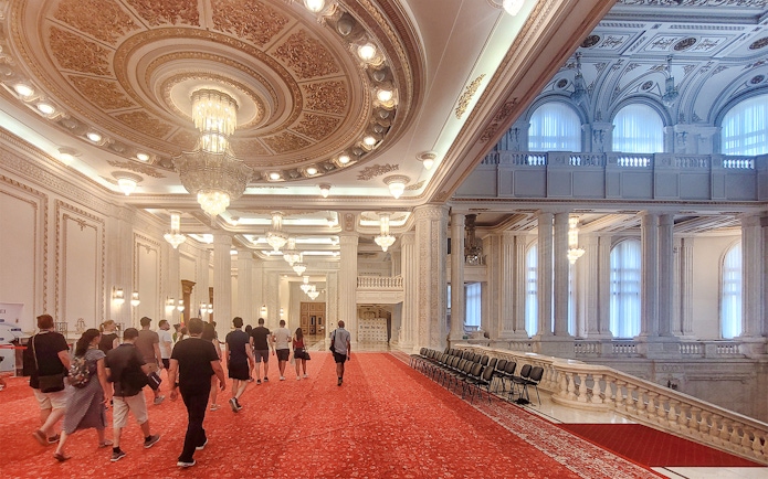 Visitors walking through ornate hall in Palace of Parliament Bucharest.