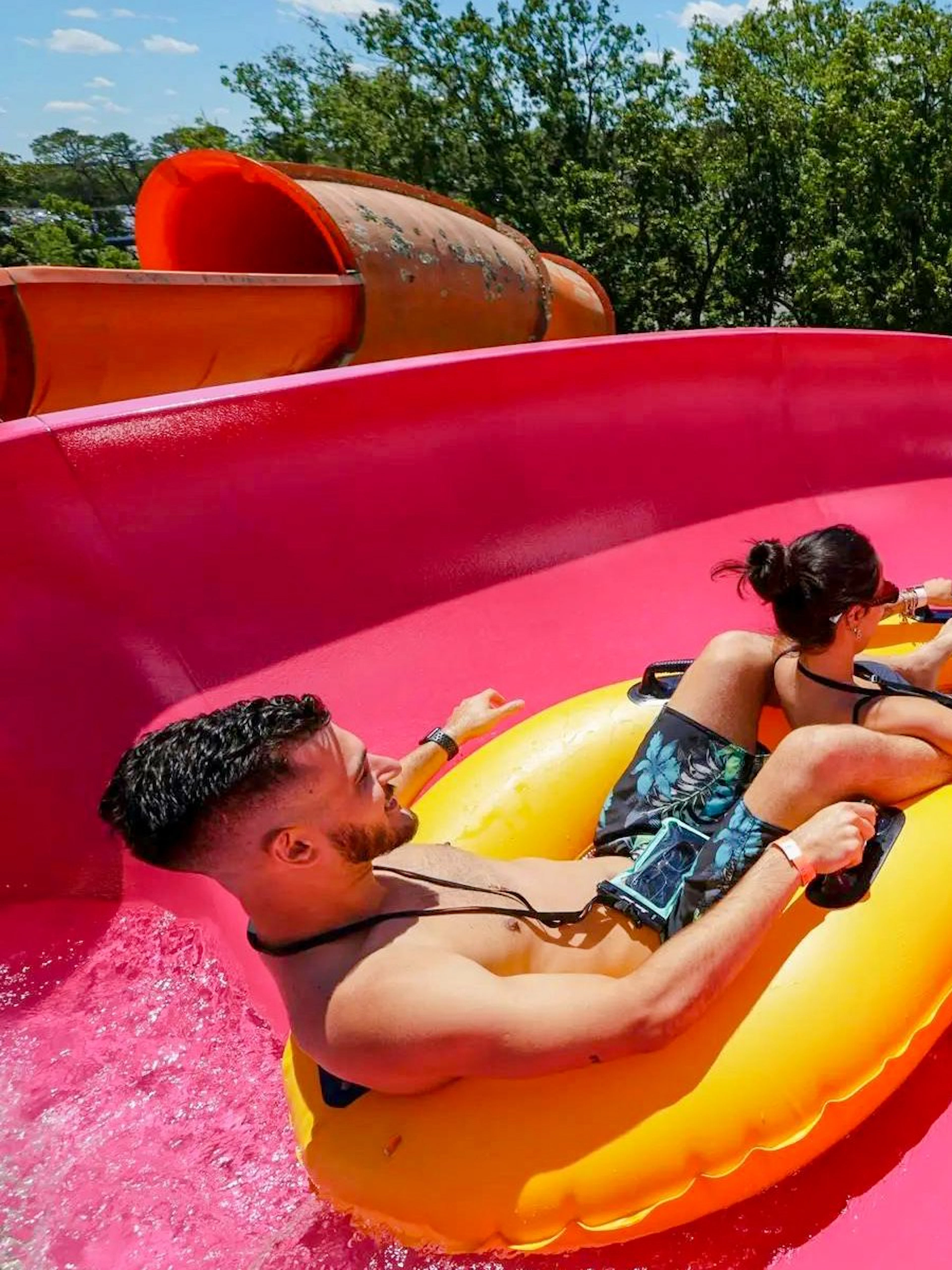Two people on a yellow raft sliding down a pink water slide at Hurricane Harbor New Jersey.