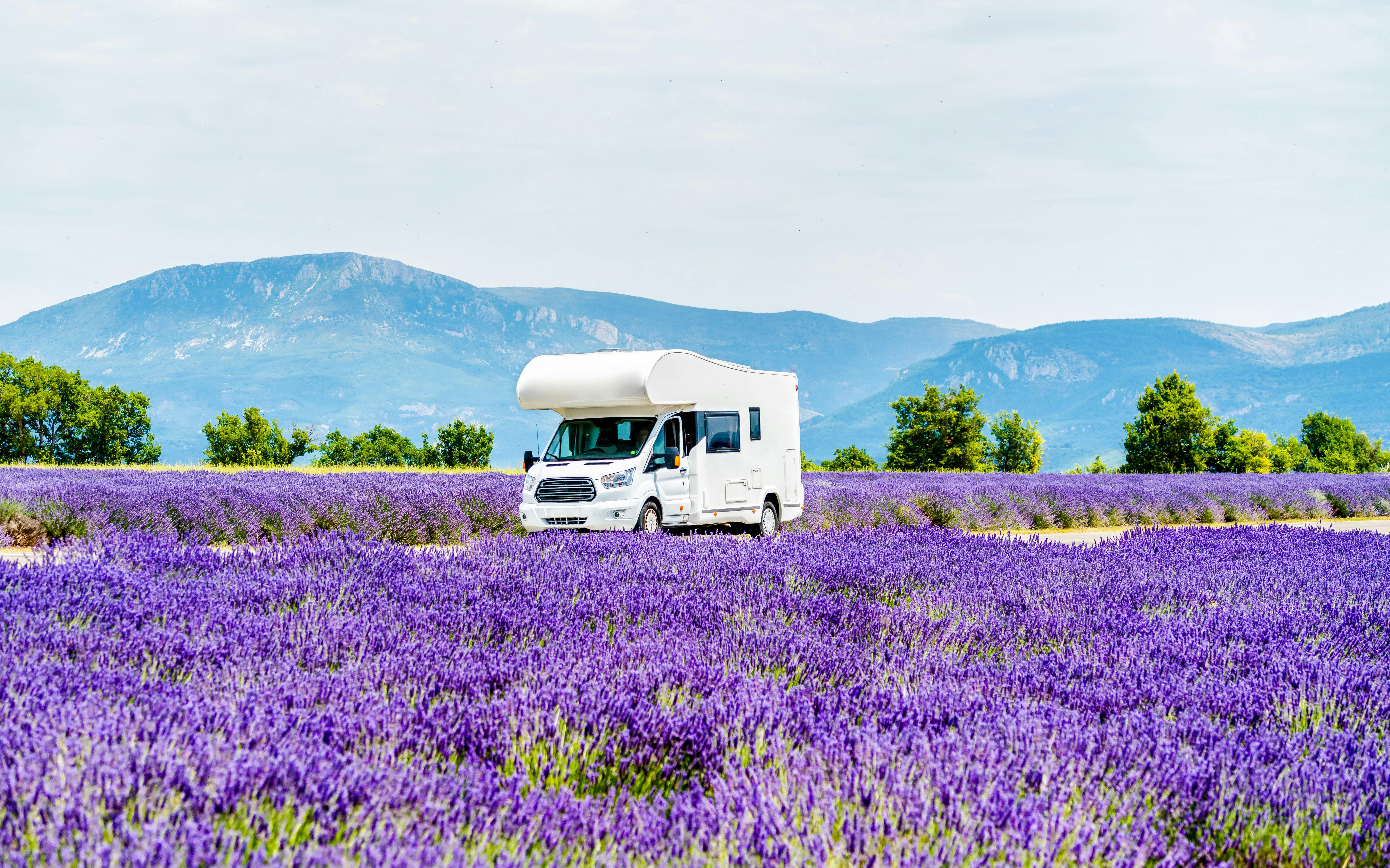 Campervan driving through lavender fields in Provence, France.