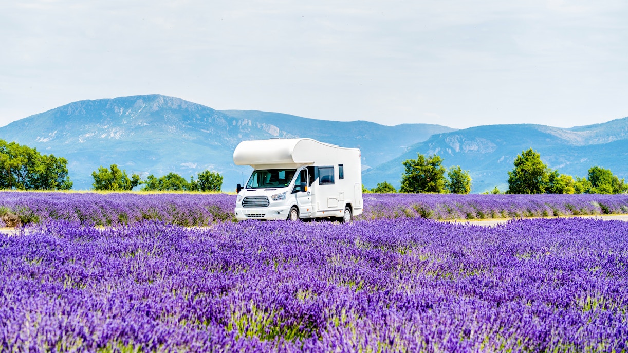 Campervan driving through lavender fields in Provence, France.