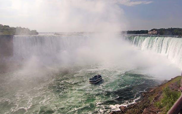 Boat approaching Niagara Falls surrounded by mist.