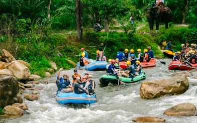 Group rafting on a river in Krabi with lush jungle and elephant in the background.