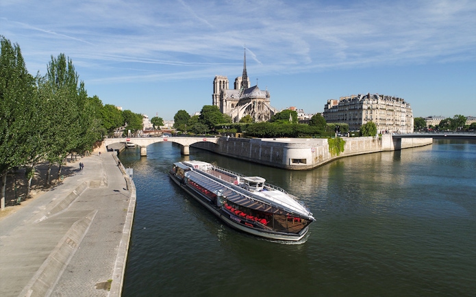 Seine River cruise boat near Notre-Dame Cathedral in Paris.