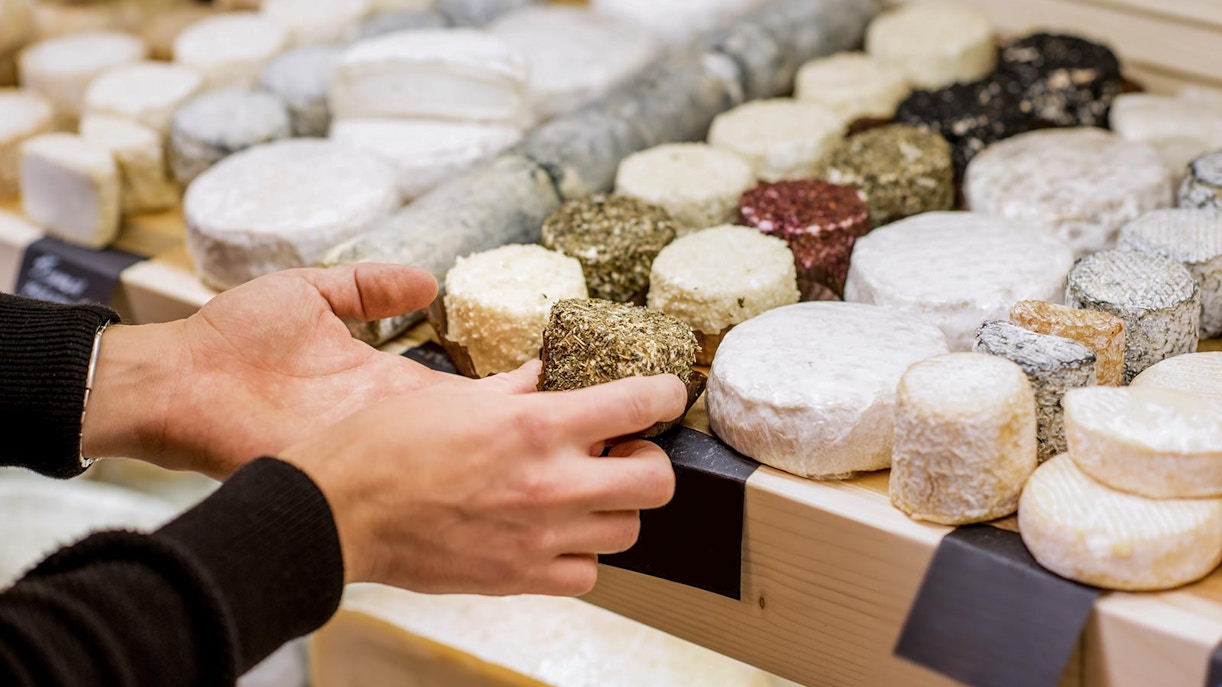 Hands selecting cheese at a market in Zaanse Schans, Netherlands.