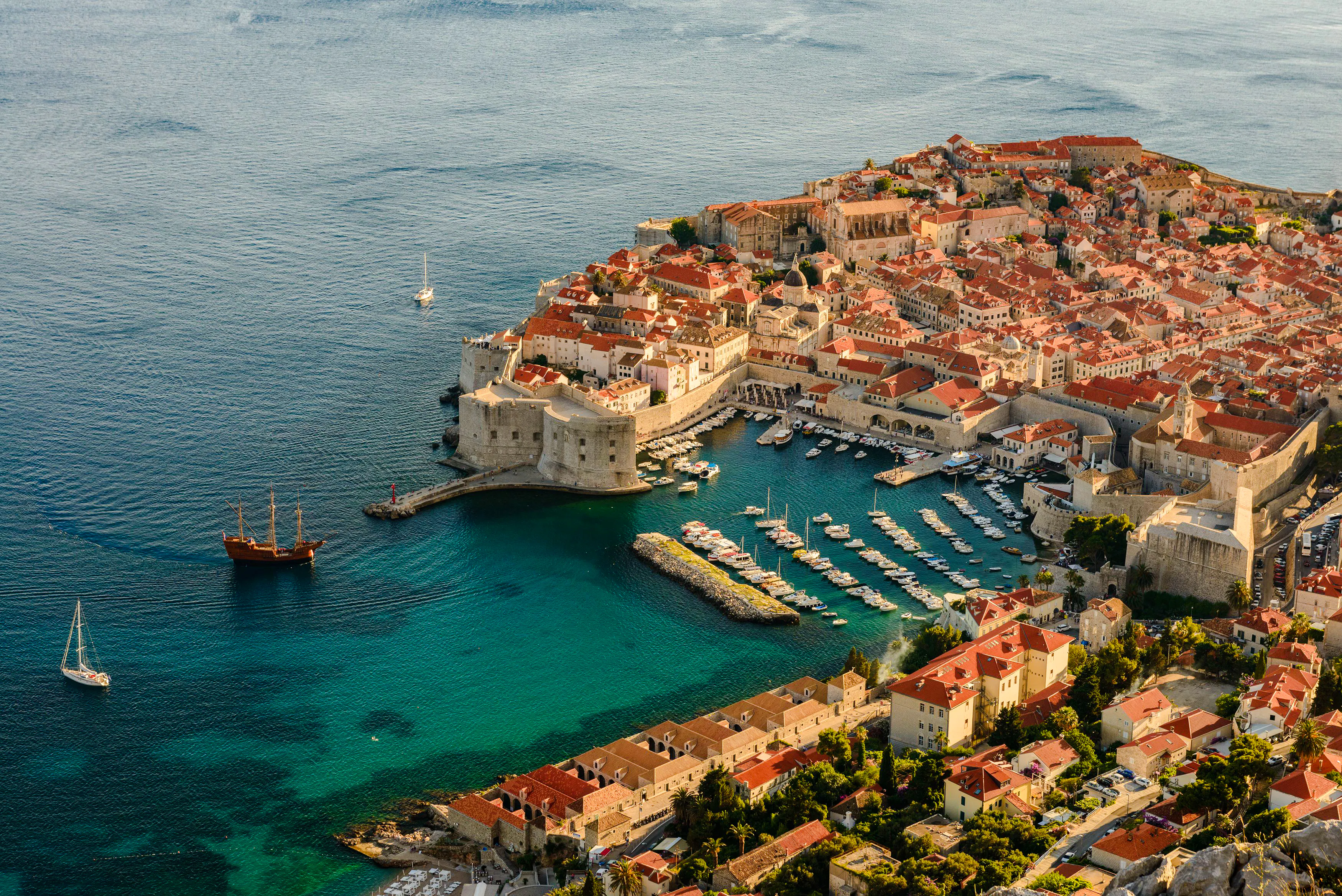 Aerial view of Dubrovnik's Old Town and harbor, highlighting historic city walls and Adriatic Sea.