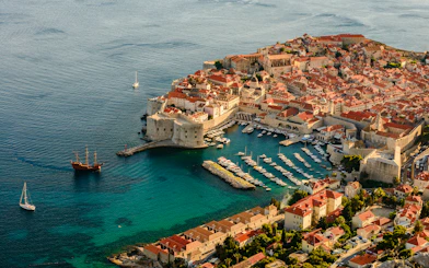 Aerial view of Dubrovnik's Old Town and harbor, highlighting historic city walls and Adriatic Sea.