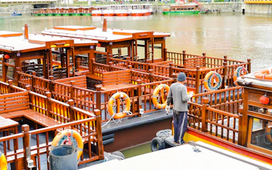 Sightseeing boat docked at Clarke Quay, Singapore River, with a person preparing for a tour.