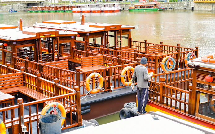 Sightseeing boat docked at Clarke Quay, Singapore River, with a person preparing for a tour.