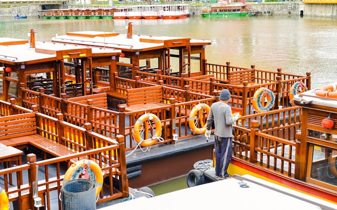 Sightseeing boat docked at Clarke Quay, Singapore River, with a person preparing for a tour.