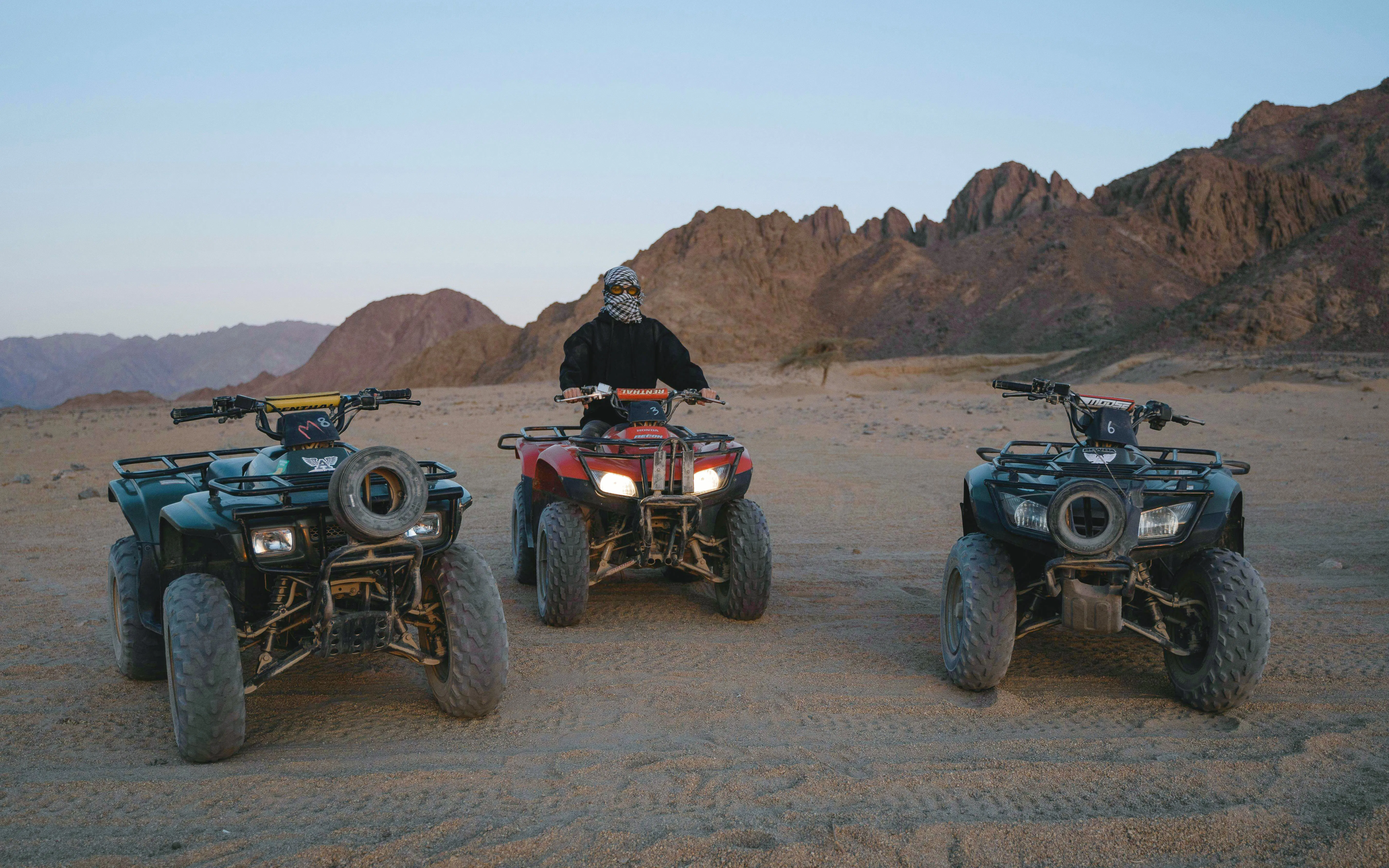 Quad bikes on desert terrain at sunrise, Marrakech tour.