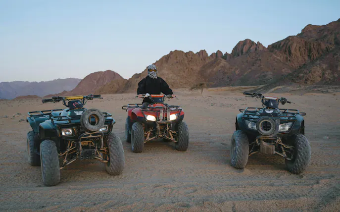 Quad bikes on desert terrain at sunrise, Marrakech tour.