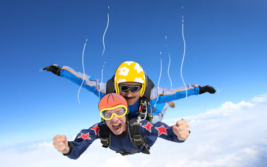 Tandem skydiving over clouds, adventure seekers in freefall.