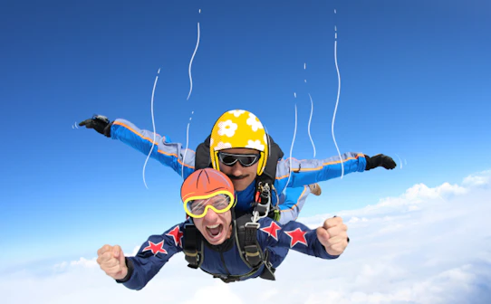 Tandem skydiving over clouds, adventure seekers in freefall.