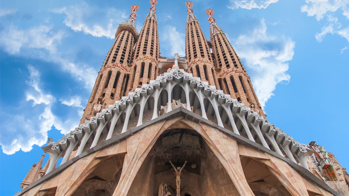 Sagrada Familia exterior towers against blue sky, Barcelona.