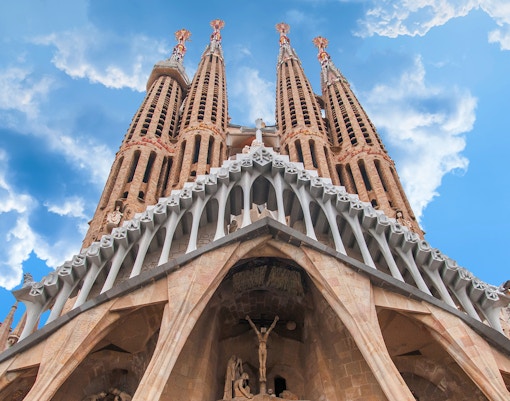 Sagrada Familia exterior towers against blue sky, Barcelona.