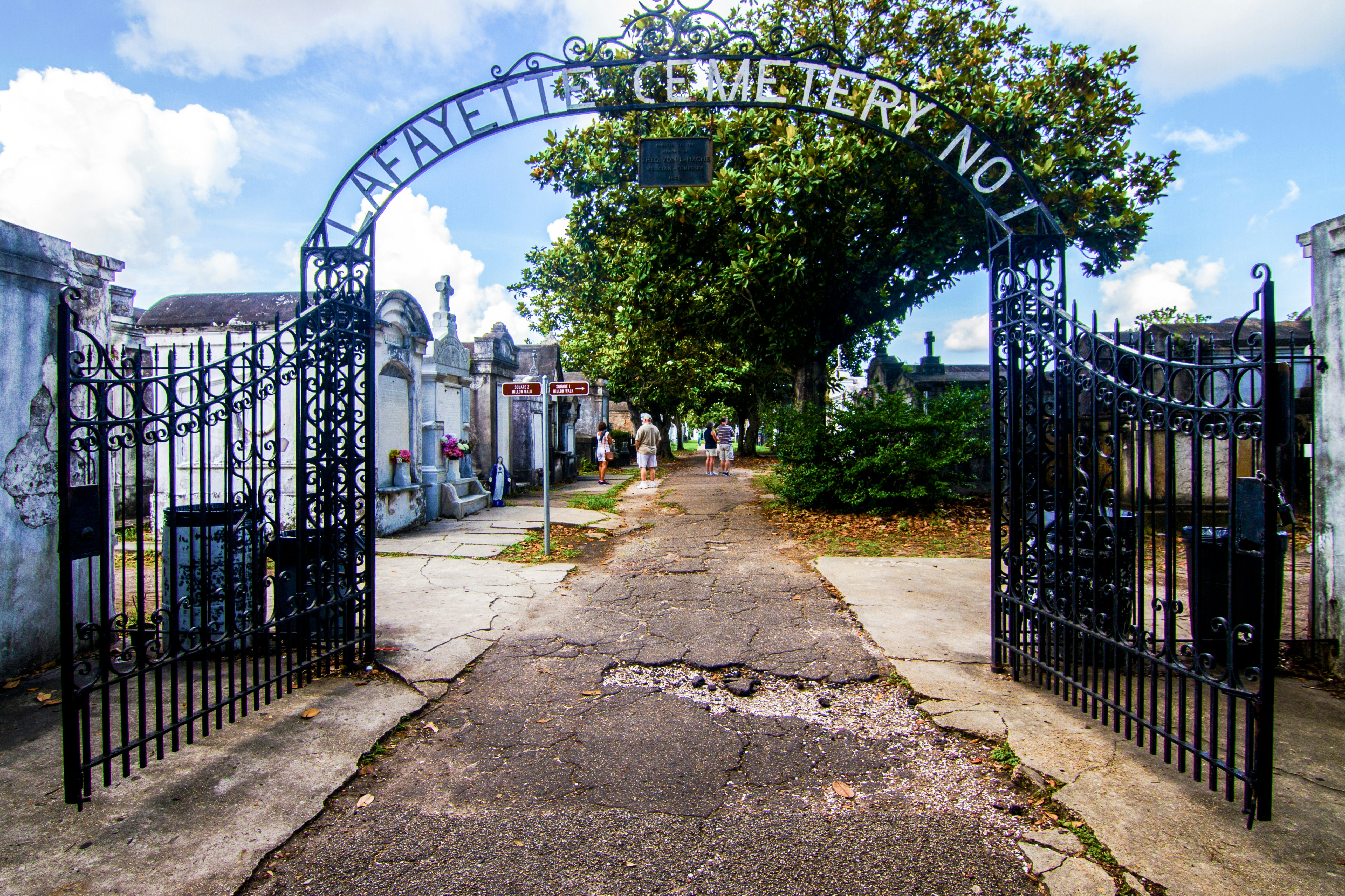 Entrance to Lafayette Cemetery with open wrought iron gates and tombs in New Orleans.