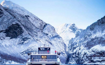 Cruise ship on Nærøyfjord with snow-covered mountains, part of Bergen to Flåm Railway tour.