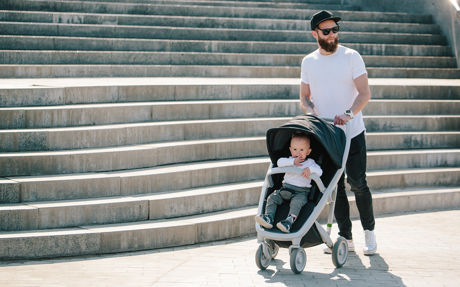 Father walking with a stroller and a baby in the city streets