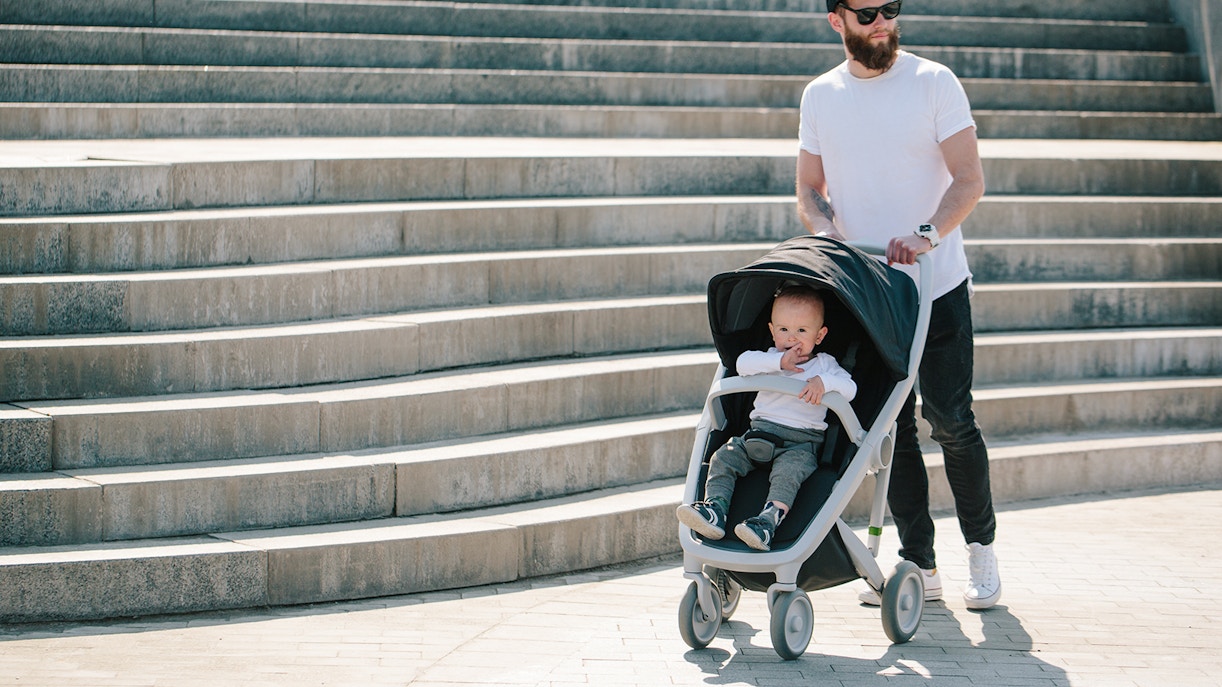 Father walking with a stroller and a baby in the city streets
