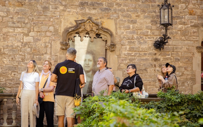 Tourists on a guided walking tour in Barcelona, observing historic architecture.