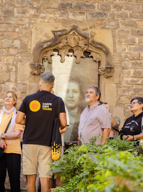 Tourists on a guided walking tour in Barcelona, observing historic architecture.
