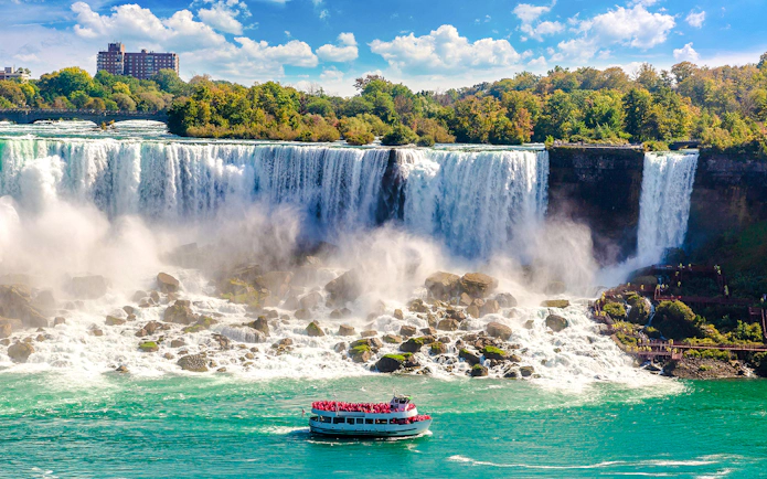 Tour boat approaching Niagara Falls USA with mist rising from the waterfall.