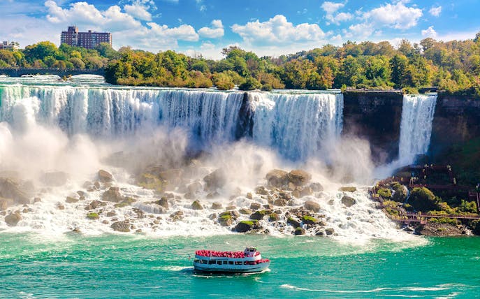 Tour boat approaching Niagara Falls USA with mist rising from the waterfall.