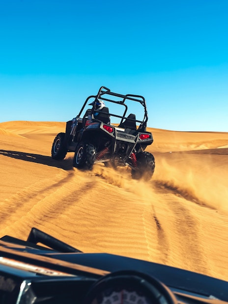 Quad biking adventure on desert dunes during a tour with hotel transfers and breakfast.