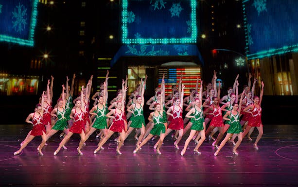 Radio City Rockettes performing in red and green costumes during Christmas Spectacular.