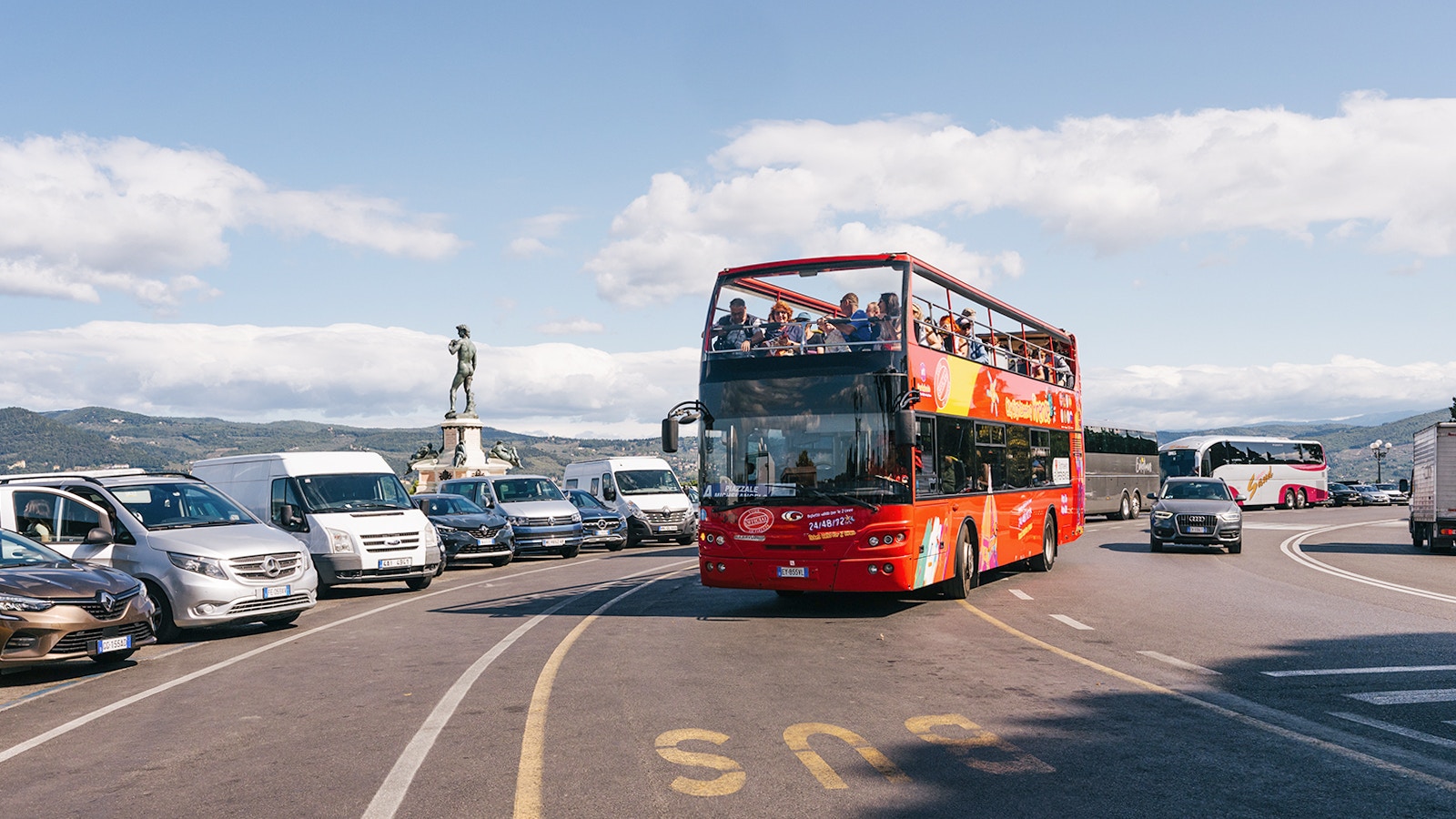 Florence cityscape with red hop-on hop-off bus near historic landmarks.