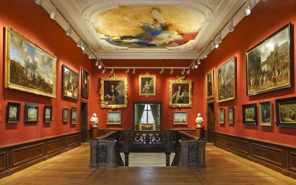 Mauritshuis museum gallery with classic paintings and ornate ceiling.