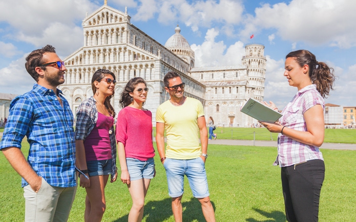 Tour guide explaining the Leaning Tower of Pisa to visitors.