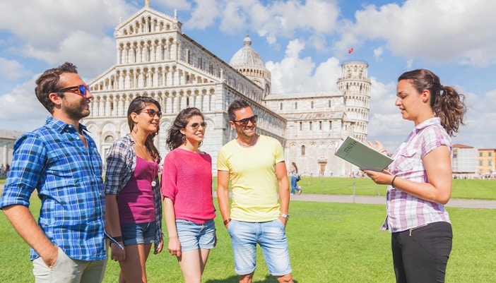 Tour guide explaining the Leaning Tower of Pisa to visitors.