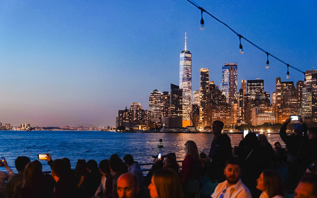 New York City skyline at night with people on a boat tour.