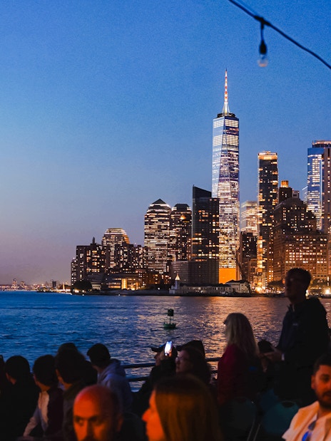 New York City skyline at night with people on a boat tour.