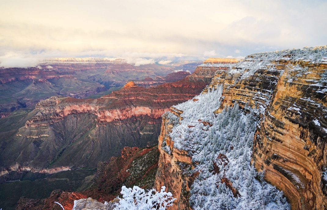 Grand Canyon covered in snow with a view of the canyon's layered rock formations.