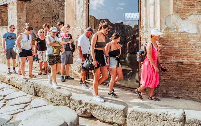 Tourists entering Pompei with skip-the-line access, ancient stone path visible.