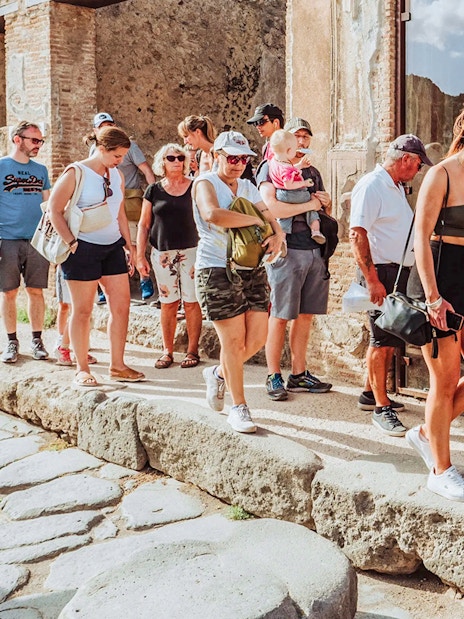 Tourists entering Pompei with skip-the-line access, ancient stone path visible.