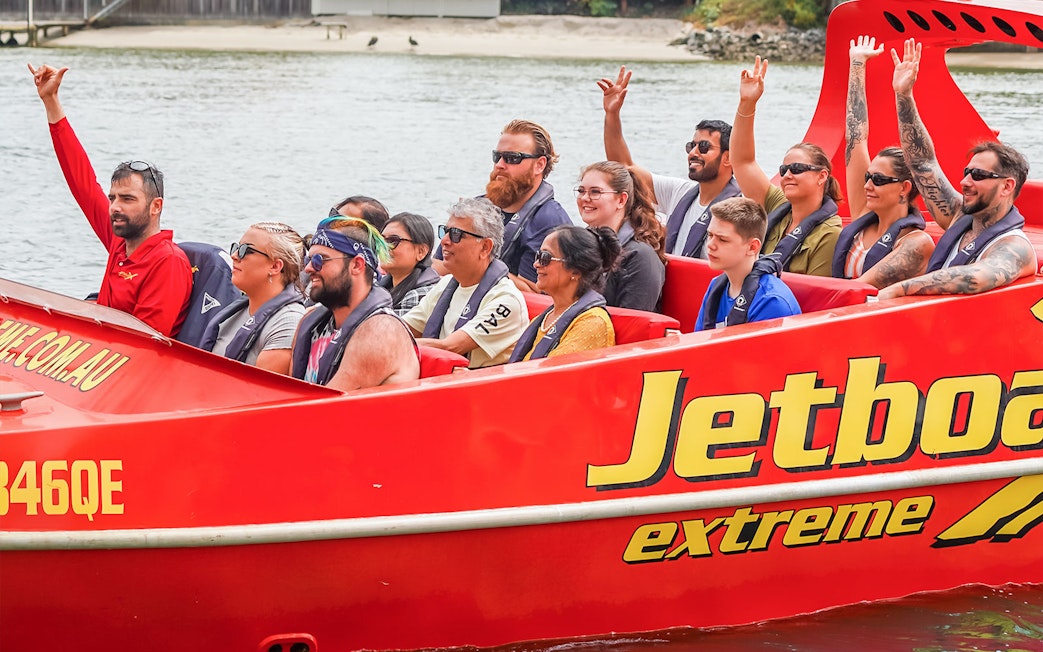 Group enjoying a thrilling jet boat ride on a river, part of the Ultimate Jet Boat Ride and Surf Lesson experience.