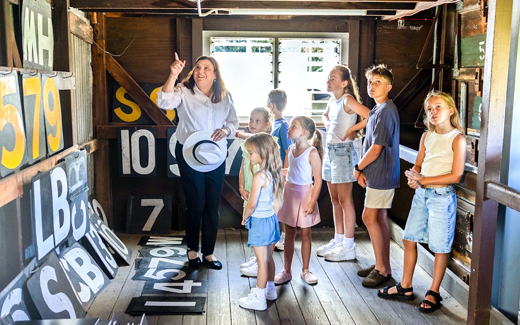 Guide explaining scoreboard numbers to children in a wooden room.