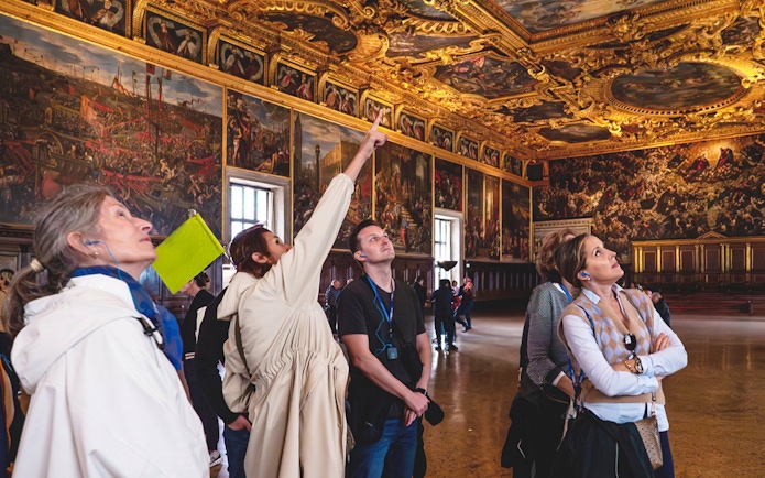Visitors admiring ornate ceiling and artwork during Doge Palace guided tour in Venice.