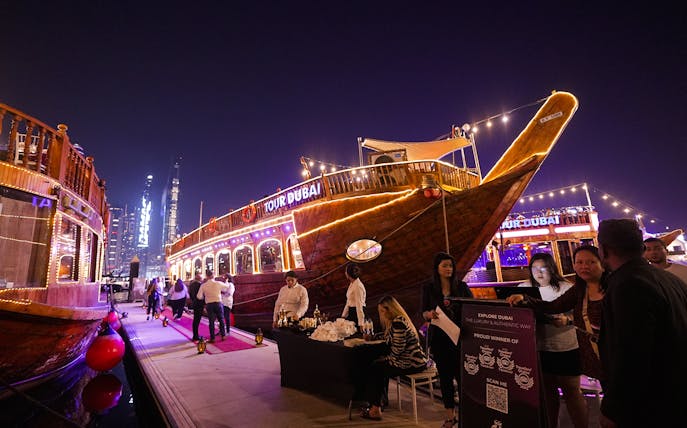 Dubai Marina dhow cruise with guests boarding for a 5-star Indian dinner experience.